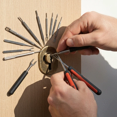 Serrurier intervenant sur une serrure de porte, gros plan sur les mains et les outils
